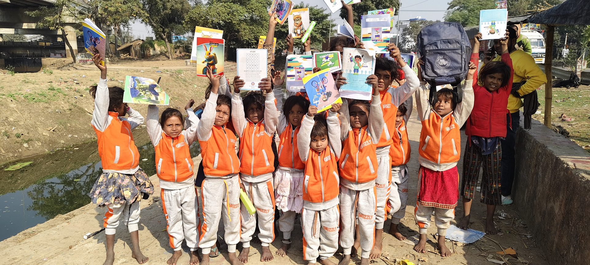 Children in orange vests holding up their books