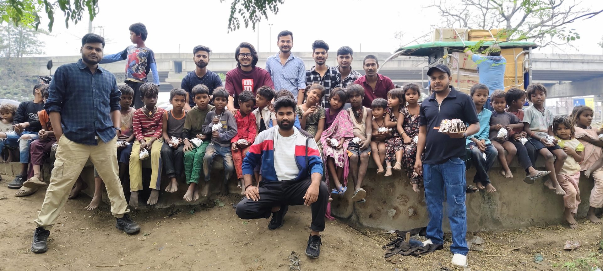 Volunteers sitting with children who received meal packets