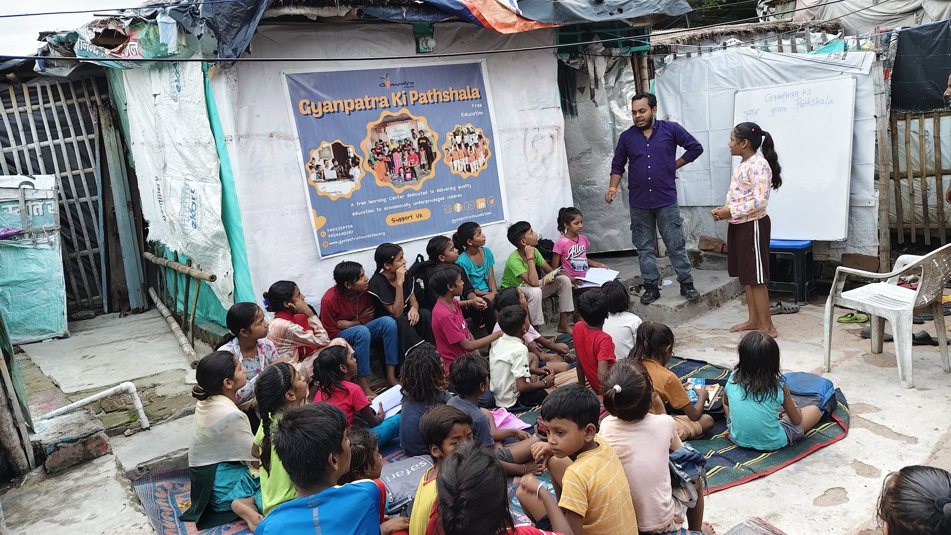 Volunteer teaching outdoors in front of the Pathshala banner