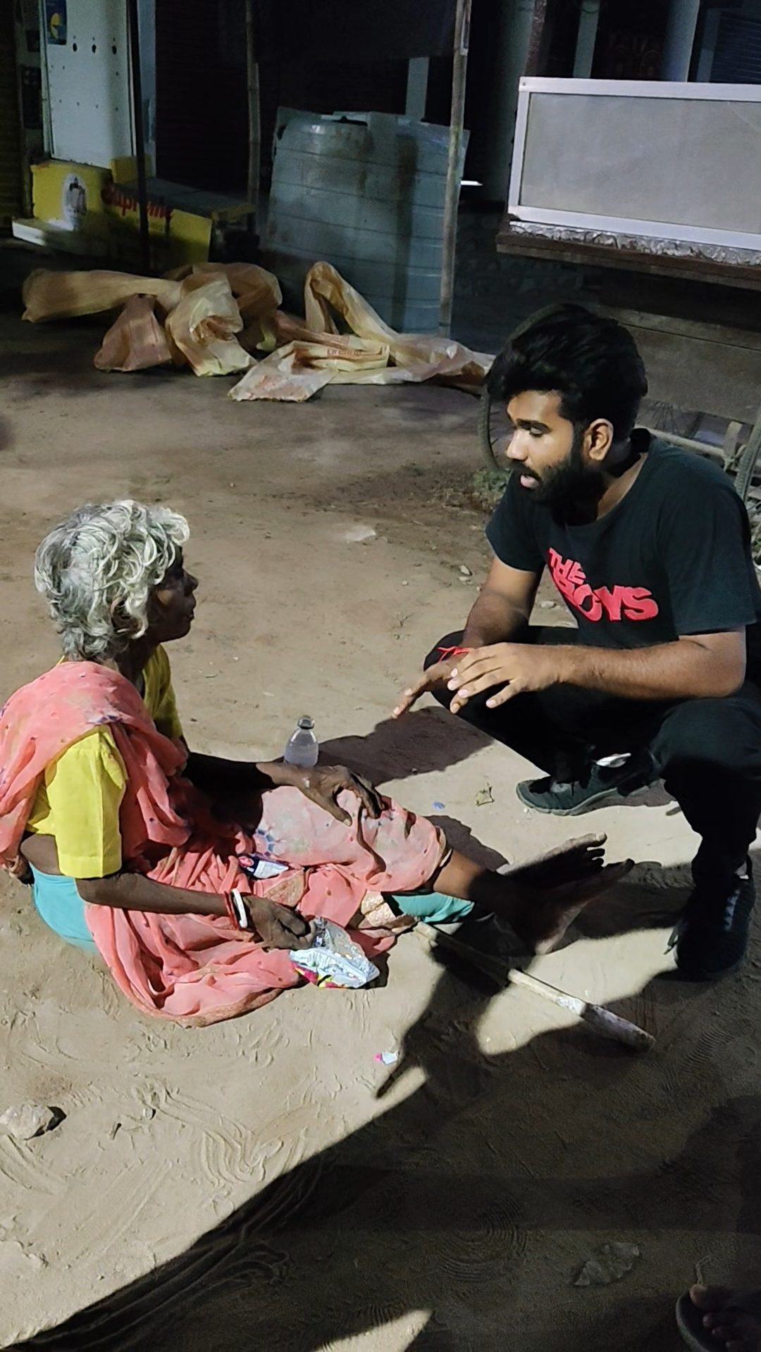 A volunteer offering help to an elderly woman on the street at night